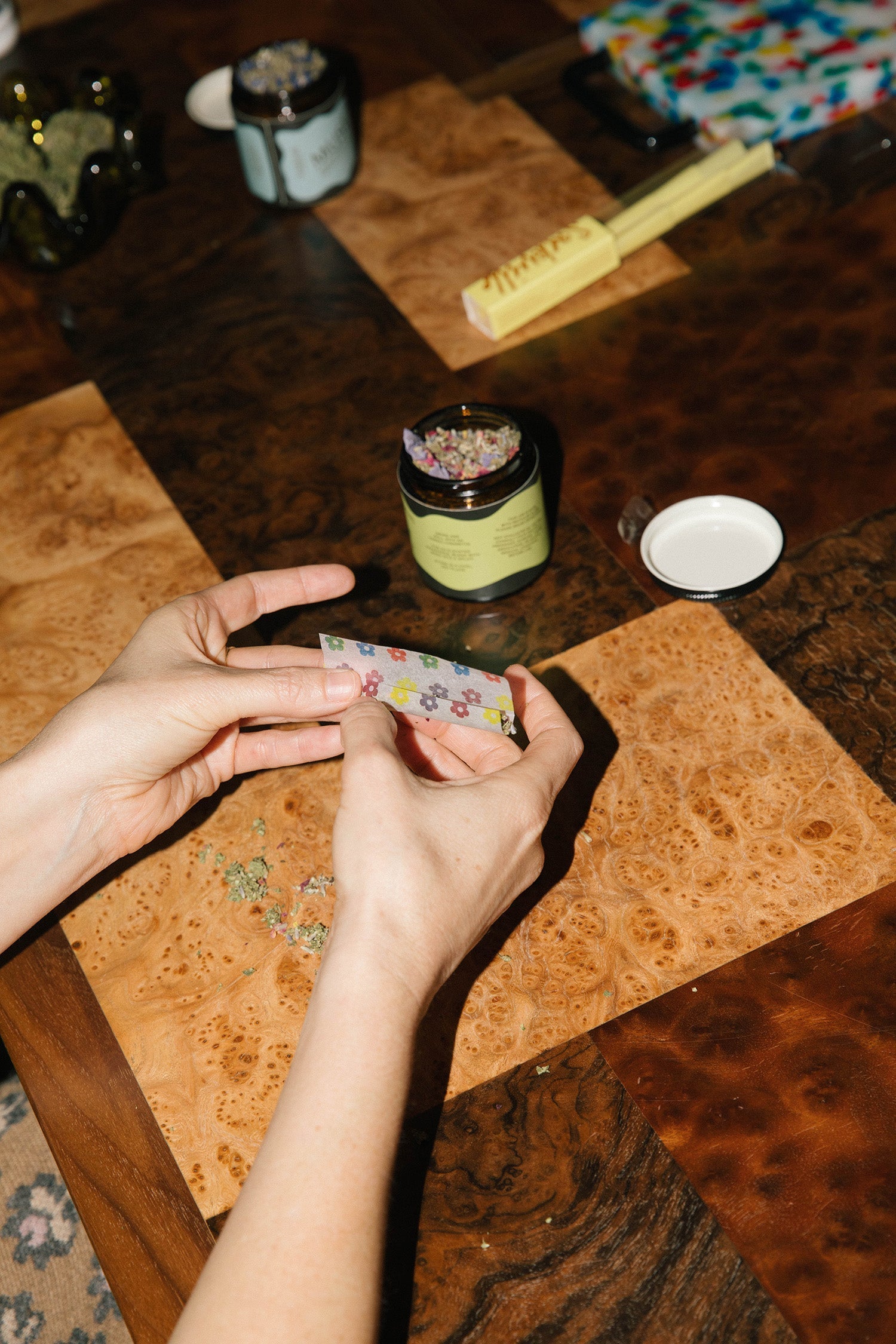 A person rolls a joint with Barbari herbal smoking blends and flower printed rolling papers.